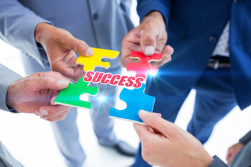 The word success against business colleagues holding piece of puzzle