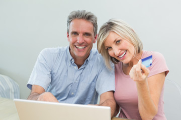 Cheerful couple doing online shopping at home