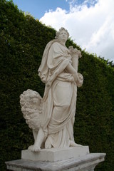 White marble statue of Eath in Versailles garden in bright summer day