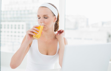 Natural pretty sportswoman enjoying orange juice