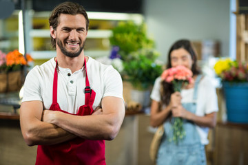 Smiling florist standing in florist shop with arms crossed