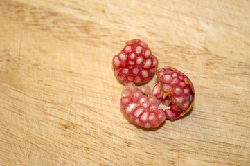 Peeled dwarf pomegranate fruits on wooden surface close up, crop of punica granatum var. nana