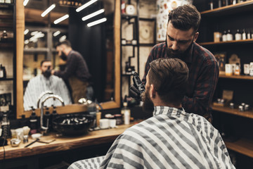 Fototapeta na wymiar Hipster young good looking man visiting barber shop. Trendy and stylish beard styling and cut.