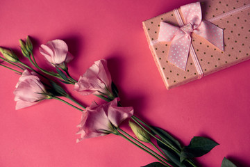 gift box with a bow and flowers on a pink background