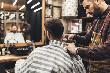 Hipster young good looking man visiting hairstylist in barber shop.