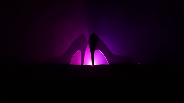 Black suede high heel women shoes on dark toned foggy background. Close up. Women power or women domination concept. Selective focus. Slider shot
