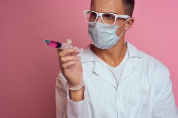 doctor in a medical mask holding a syringe in his hand