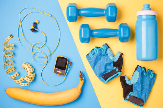 Photo of player, dumbbells, bottle of water, a centimeter tape, gloves, banana on blue and yellow background
