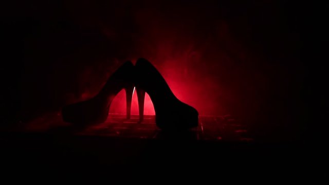 Black suede high heel women shoes on dark toned foggy background. Close up. Women power or women domination concept. Selective focus. Slider shot
