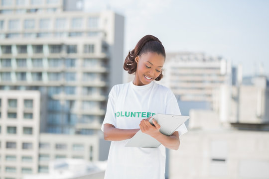 Smiling volunteer woman taking notes holding clipboard 