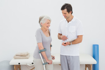 Therapist discussing reports with a disabled senior patient