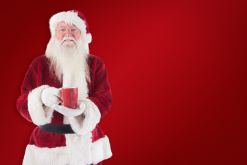 Santa holds a red cup against red background
