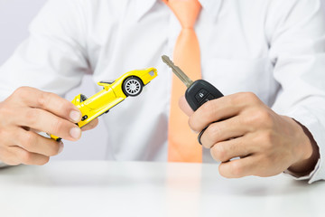 Businessman holding a car keys and miniature car model, Auto business and financial concept