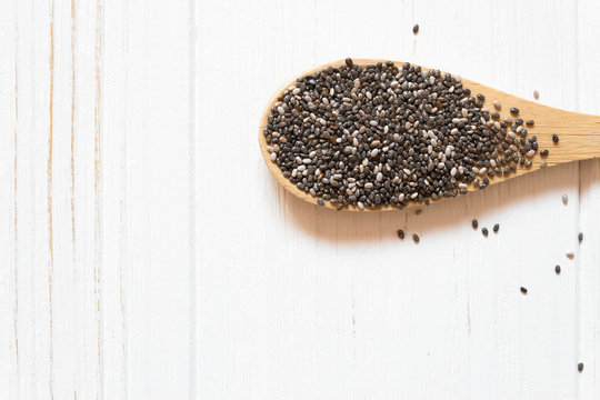 Macro Chia seeds in wooden spoon. Superfood with copy space on white background