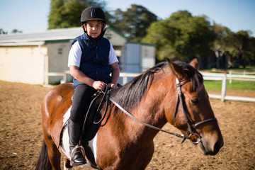 Fototapeta premium Boy riding a horse in the ranch