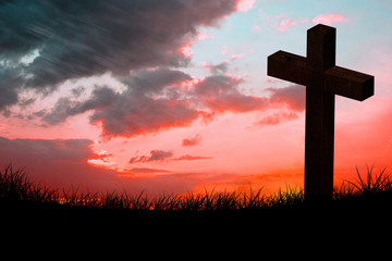 Wooden cross against red sky over grass