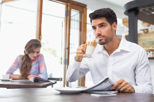 Man With Drink And Newspaper In Coffee Shop