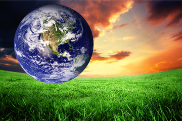 Obraz na płótnie Canvas earth against green field under orange sky