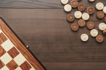 top view of wooden draughts game on brown table background