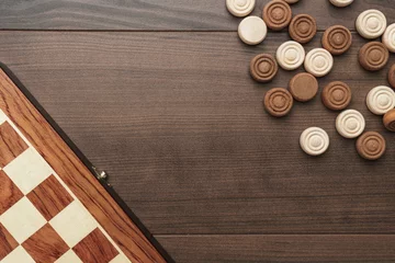 Foto op Canvas top view of wooden draughts game on brown table background © Ruslan Grumble