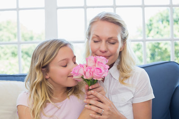 Mother and daughter smelling roses on sofa