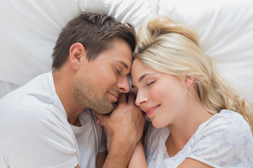 Loving couple lying in bed with eyes closed