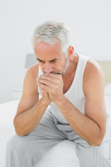 Thoughtful mature man sitting in bed