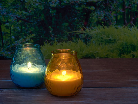Blue and yellow citronella candles lit in the garden are being used to keep mosquitoes at bay in late evening