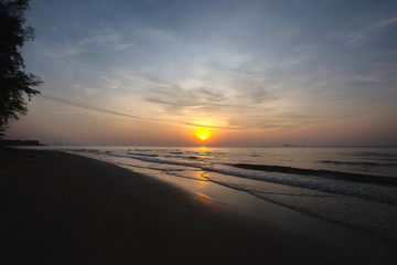 Nice sky, clouds and sun above the beautiful sea and sand beach with little waves at the morning moment.