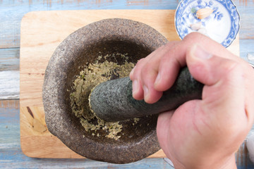 Chef pound coriander,pepper and garlic with pestle on mortar