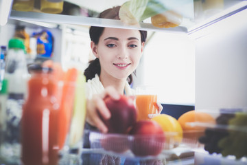 Obraz na płótnie Canvas Portrait of female standing near open fridge full of healthy food, vegetables and fruits. Portrait of female