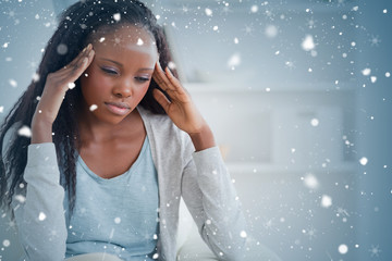 Composite image of woman experiencing a headache against snow falling