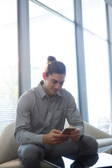 Male executive using mobile phone in waiting area