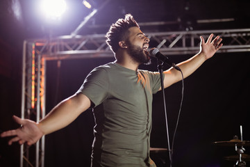 Male singer with arms outstretched performing at nightclub