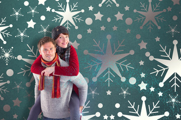 Man giving girlfriend piggy back against snowflake wallpaper pattern