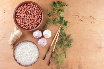 Chinese raw food ingredients, nuts, vegetables, ginger root. Fresh greens, dill and parsley. Rice and spices on a wooden background. Garlic and onion for cooking. Copy space. Art