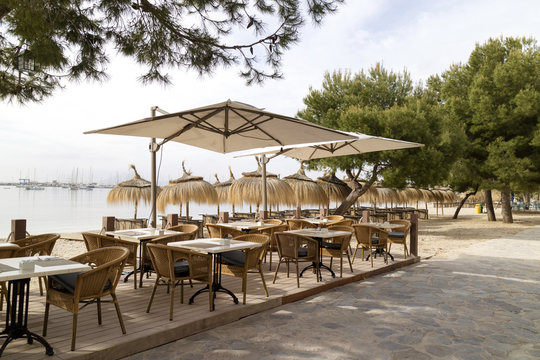 Porto Pollensa, Mallorca, Spain. 2018. Beachside tables and chairs set for breakfast in an early morning light.