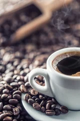 Keuken foto achterwand Koffie Kopje zwarte koffie met bonen op houten tafel