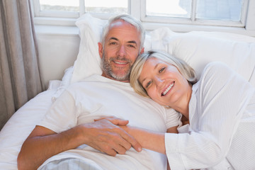 Fototapeta na wymiar Smiling relaxed mature couple lying in bed