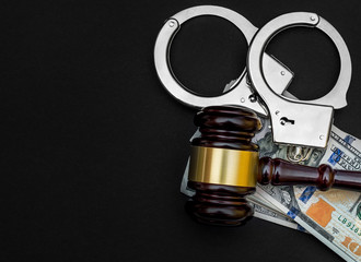 Gavel with handcuffs and money on black. Top view. Copy space for text.