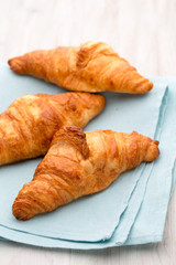 Tasty buttery croissants on old wooden table.