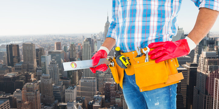 Midsection of handyman holding spirit level against new york