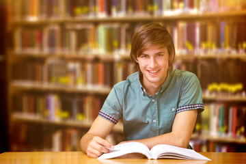 Student sitting in library reading  against close up of a bookshelf