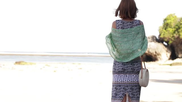 Woman with fashionable stylish yellow white bag on the beach. Tropical island of Bali. Handmade Rattan eco handbag HD footage.