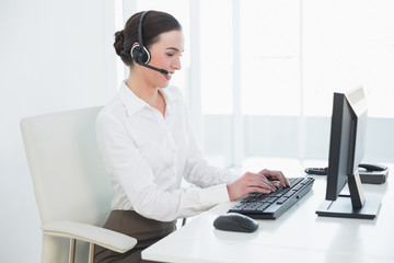 Businesswoman wearing headset while using computer