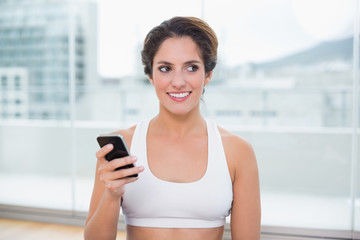 Sporty happy brunette holding smartphone