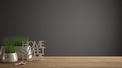 Wooden table, desk or shelf with potted grass plant, house keys and 3D letters making the words home sweet home, gray copy space background