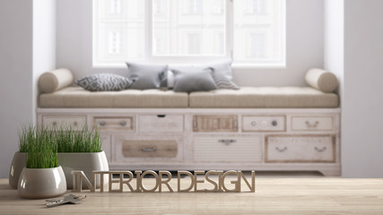 Wooden table, desk or shelf with potted grass plant, house keys and 3D letters making the words interior design, over blurred scandinavian sofa, project concept copy space background