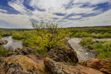 Naklejka na ściany i meble Rocky landscape near the Mihiia River. The mountains and the river Southern Bug River are surrounded by trees and grasses. Ukraine, Pervomaisk.