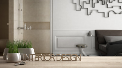 Wooden table, desk or shelf with potted grass plant, house keys and 3D letters making the words interior design, over blurred modern bedroom, project concept copy space background